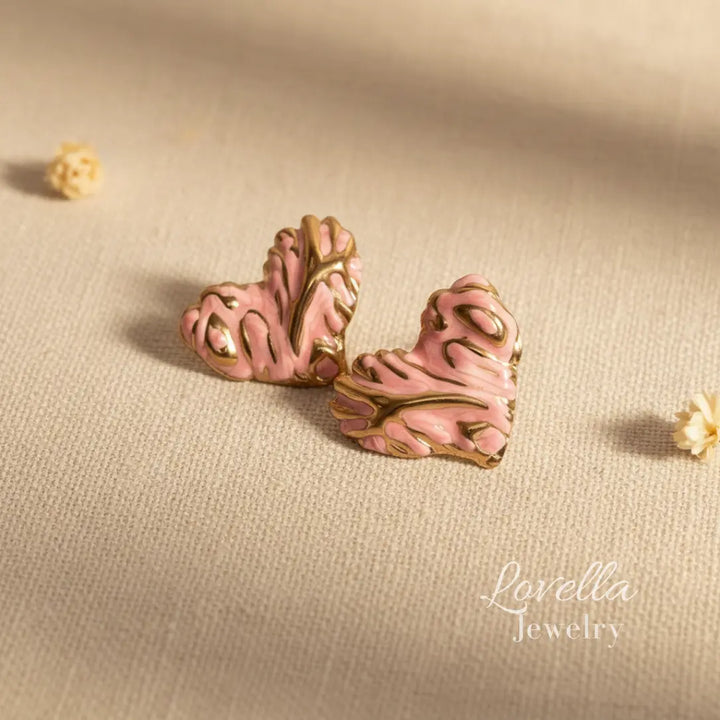 Pink and gold earrings on a beige fabric background