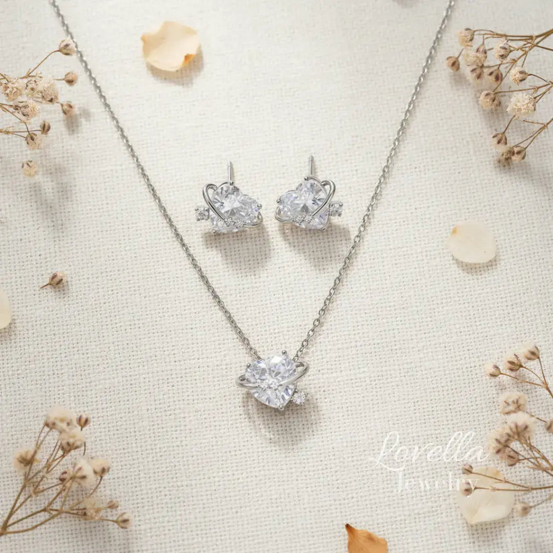 Silver necklace and earrings set on a textured surface with dried flowers.