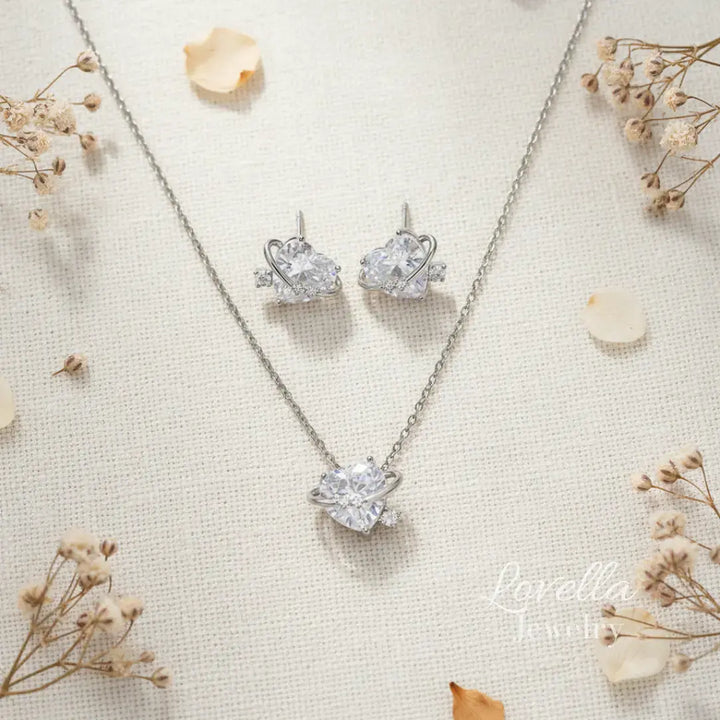 Silver necklace and earrings set on a textured surface with dried flowers.