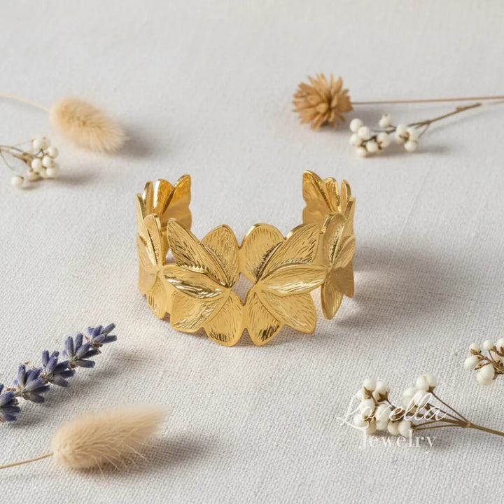 Gold leaf bracelet on a light surface with dried flowers
