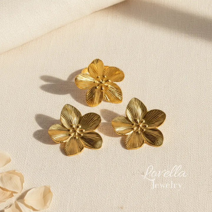Gold floral earrings on a beige fabric background with 'Lavella Jewels' branding.