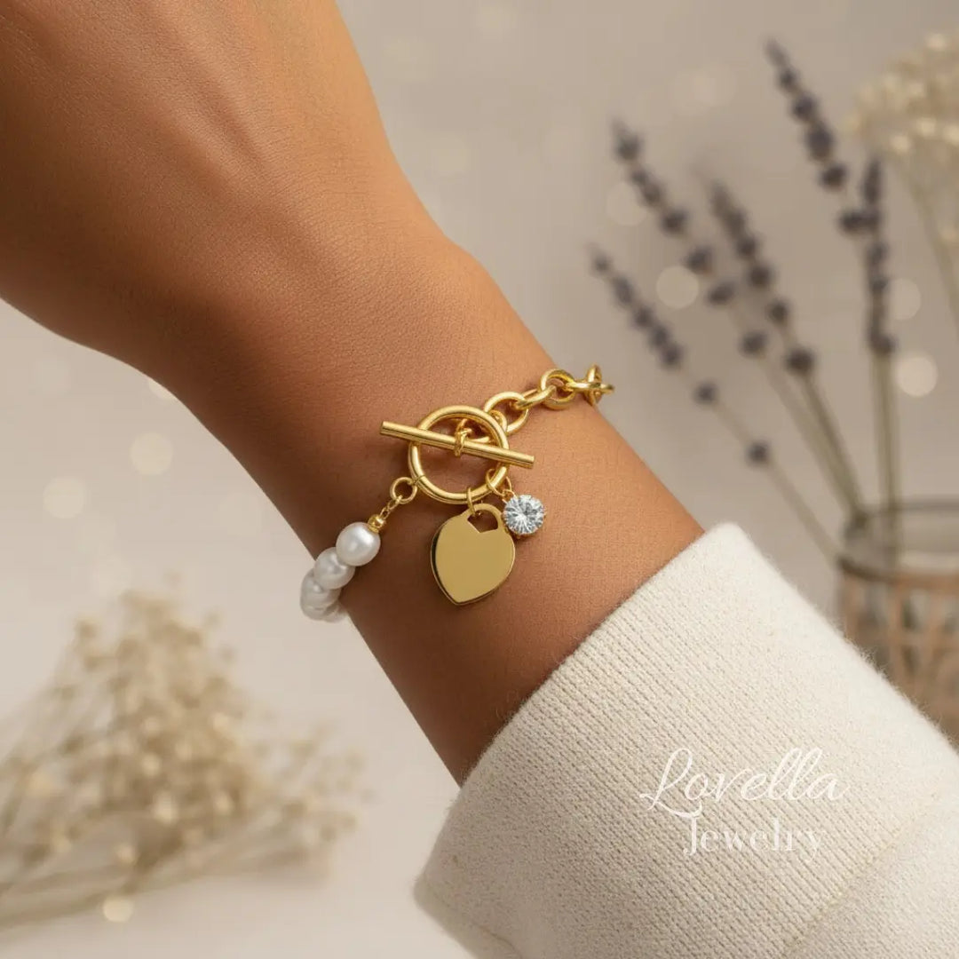 Gold bracelet with heart charm and pearl beads on a wrist, brand 'Lavella' visible.