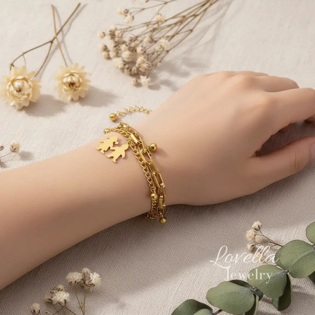 Gold bracelet on a wrist with flowers and leaves in the background, featuring Lovella Jewelry.