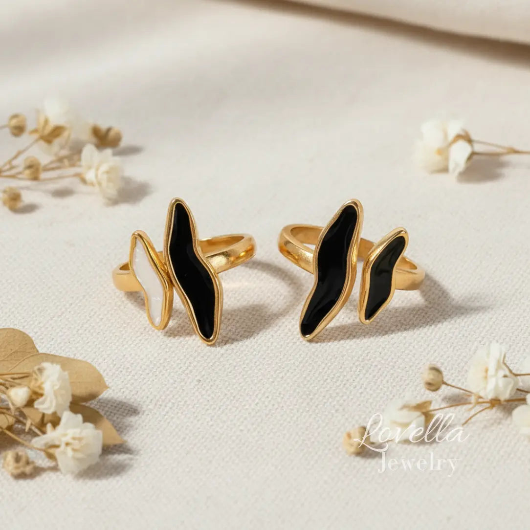 Two gold rings with black stones on a light background with flowers.
