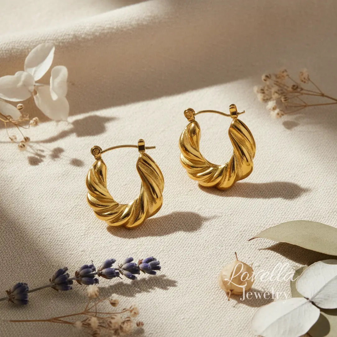 Gold hoop earrings on a light surface with floral elements