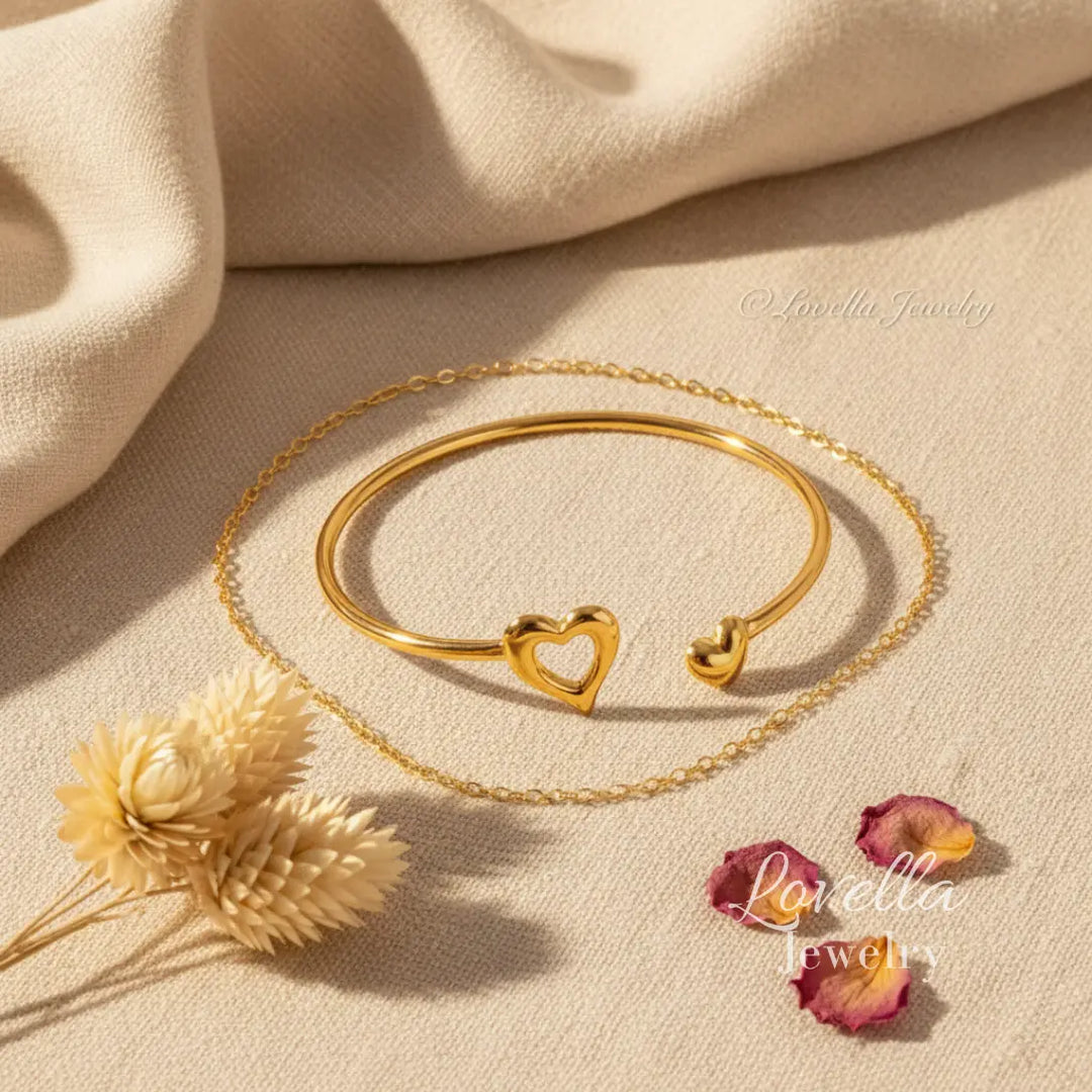 Gold bracelet with heart-shaped ends on a beige fabric background, featuring Lovella Jewelry branding.