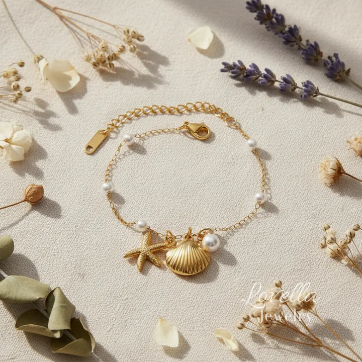Gold bracelet with starfish and shell charms on a textured surface with flowers