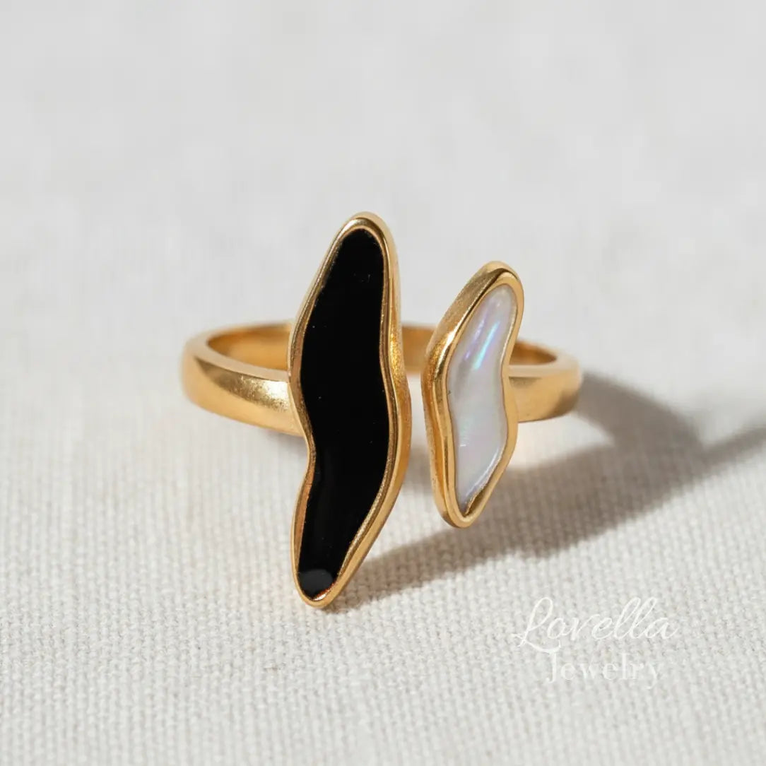 Gold ring with black and white stone on a light background