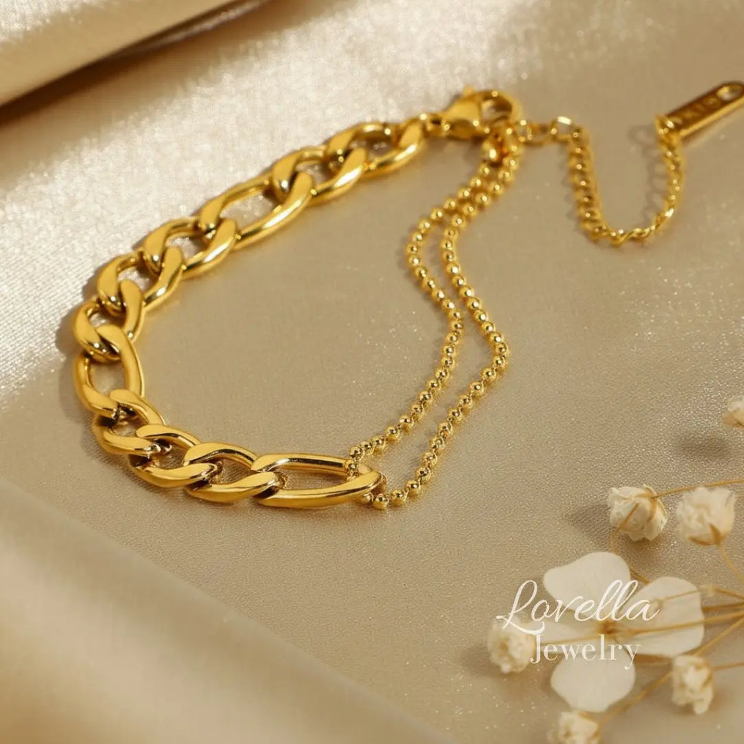 Gold chain bracelet on a beige surface with 'Lovella Jewelry' branding.