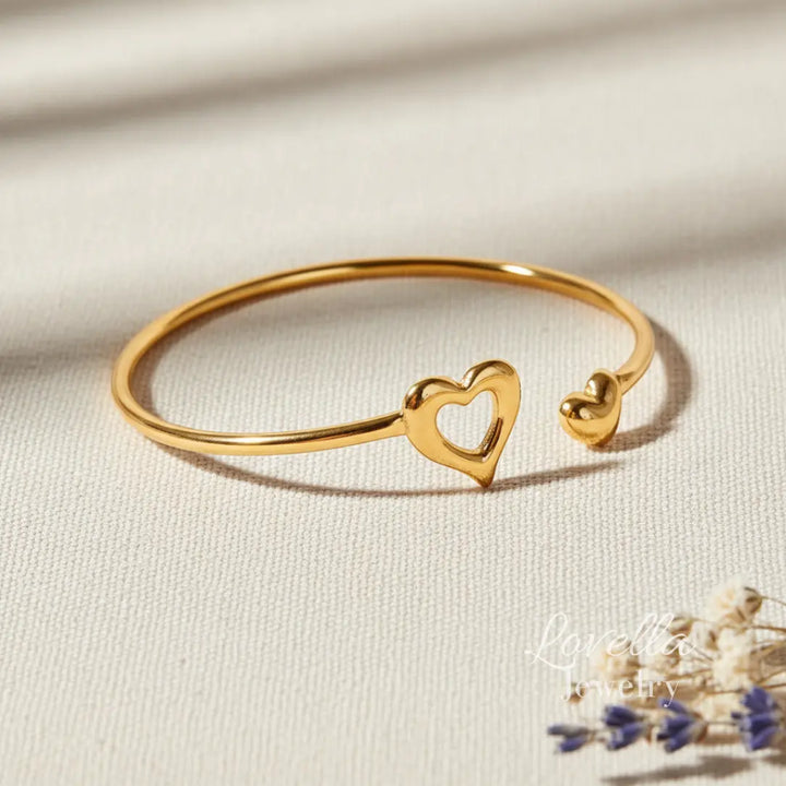 Gold bracelet with heart designs on a beige fabric background