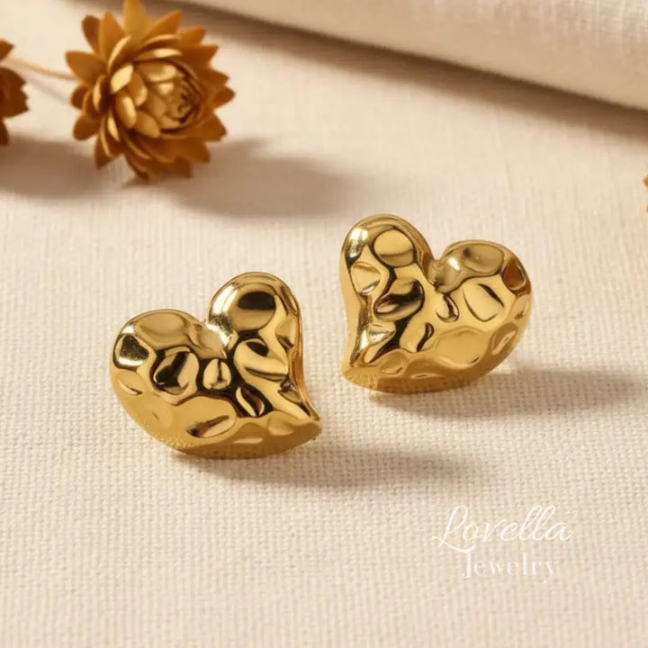 Gold heart-shaped earrings on a beige surface with 'Lavelia Jewelry' branding.