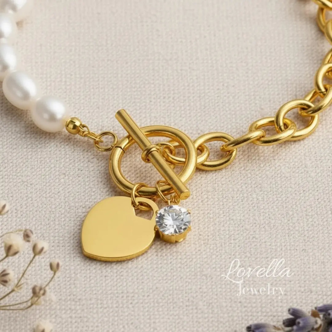 Gold bracelet with heart charm and crystal on a beige background, featuring Lovella Jewelry.