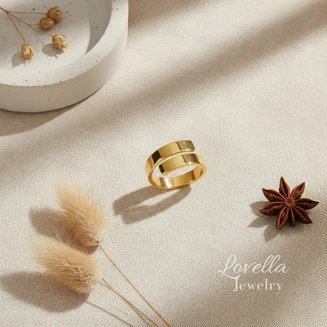 Gold ring on a beige surface with decorative elements and 'Lovella Jewelry' branding.