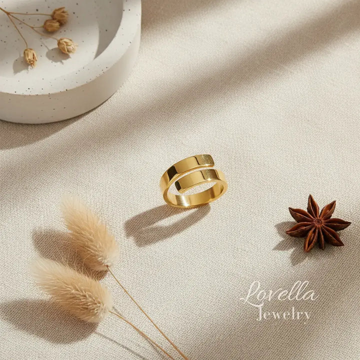 Gold ring on a beige surface with decorative elements and 'Lovella Jewelry' branding.