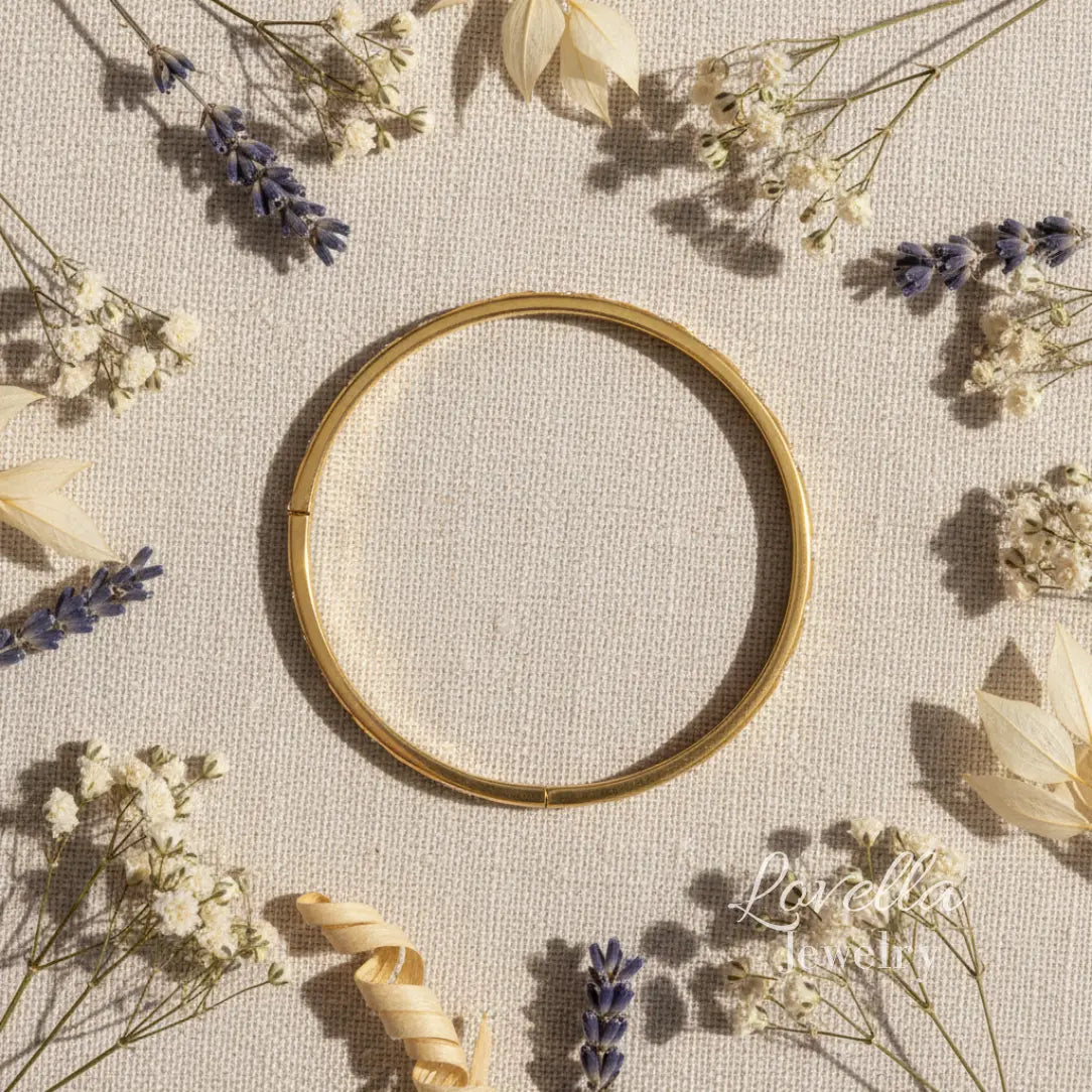 Gold bracelet on a textured surface with dried flowers
