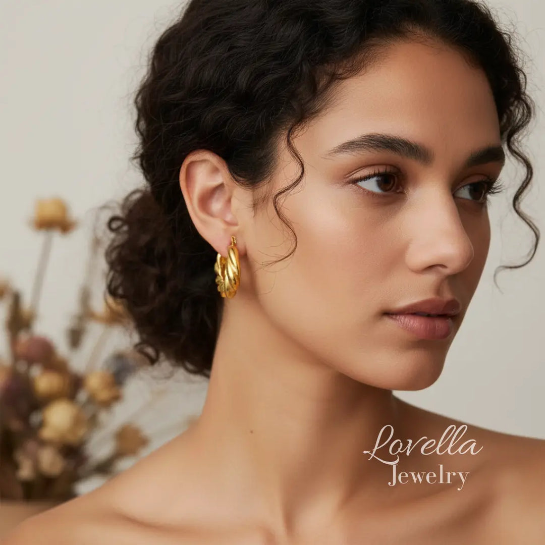 Woman wearing gold hoop earrings with a blurred background and 'Lovella Jewelry' branding.