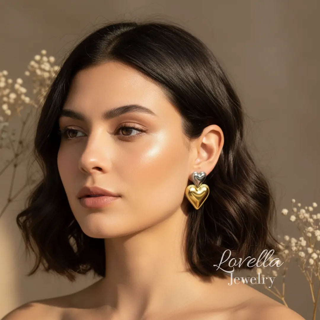 Woman wearing heart-shaped earrings with a neutral background and Lovella Jewelry' branding.