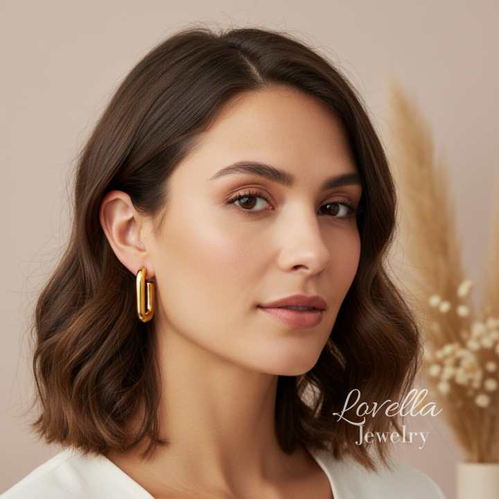 Woman wearing gold earrings with a blurred background and 'Lovella Jewelry' branding.