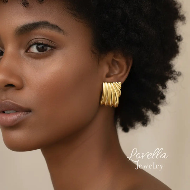 Woman wearing gold earrings with 'Lovella Jewelry' logo