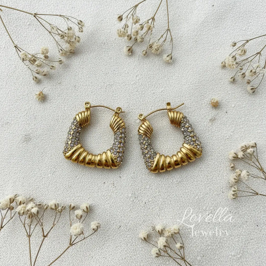 Gold hoop earrings on a light background with small flowers