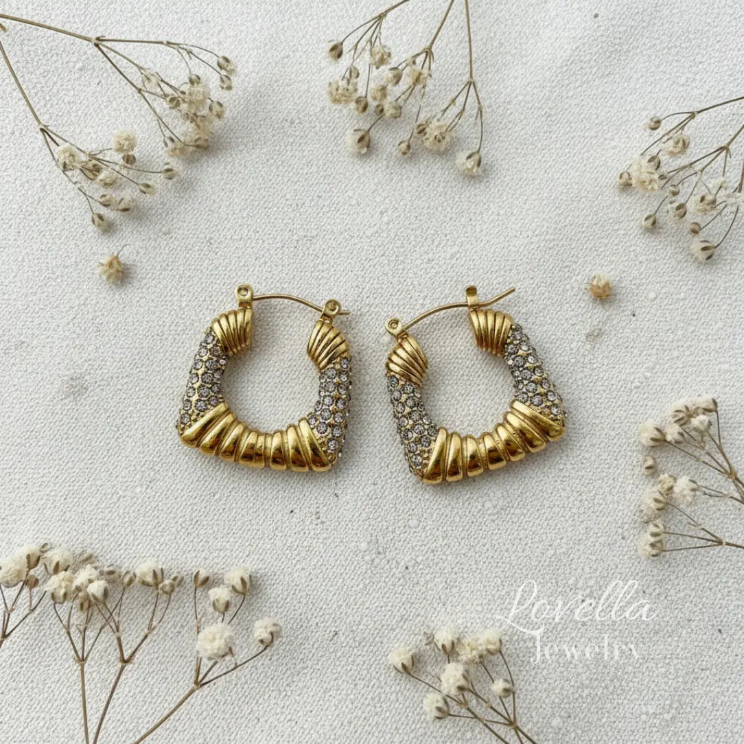 Gold hoop earrings on a light background with small flowers