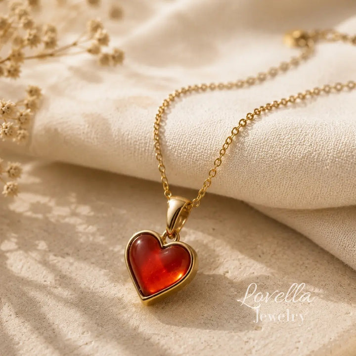 Amore Heart Necklace with glossy red heart pendant styled on cream stone and soft fabric