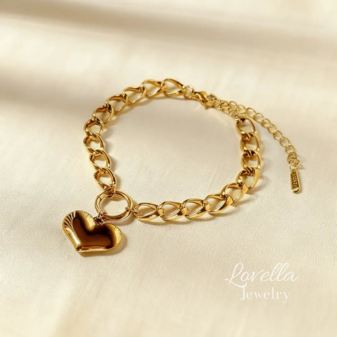 Gold chain bracelet with a heart charm on a beige background, branded 'Lovella Jewelry'.