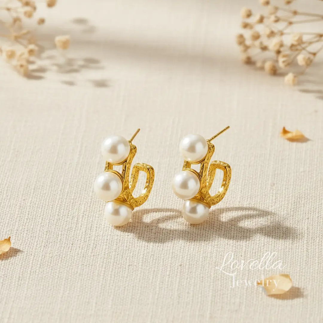 Gold earrings with pearls on a beige background