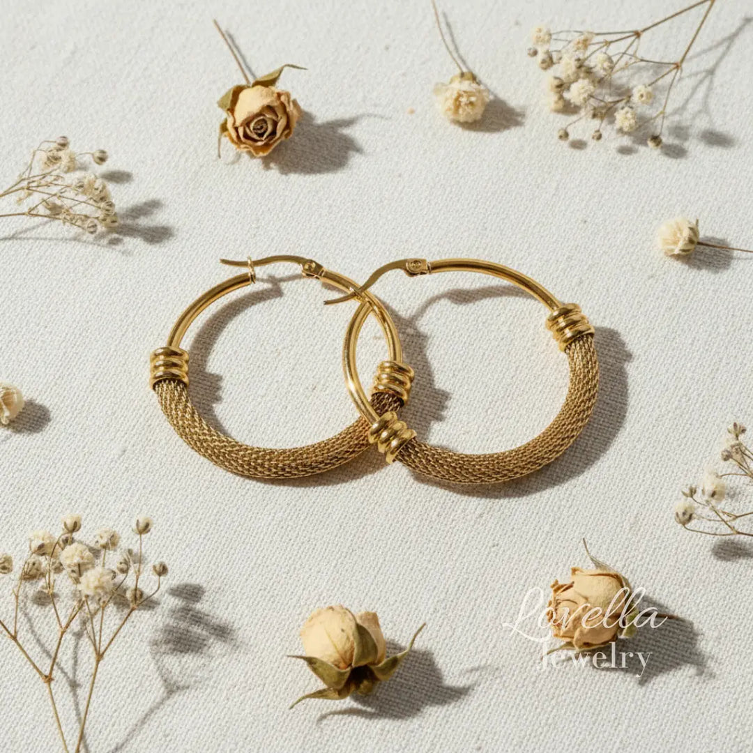 Gold hoop earrings on a light background with dried flowers