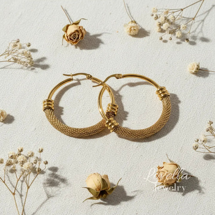 Gold hoop earrings on a light background with dried flowers