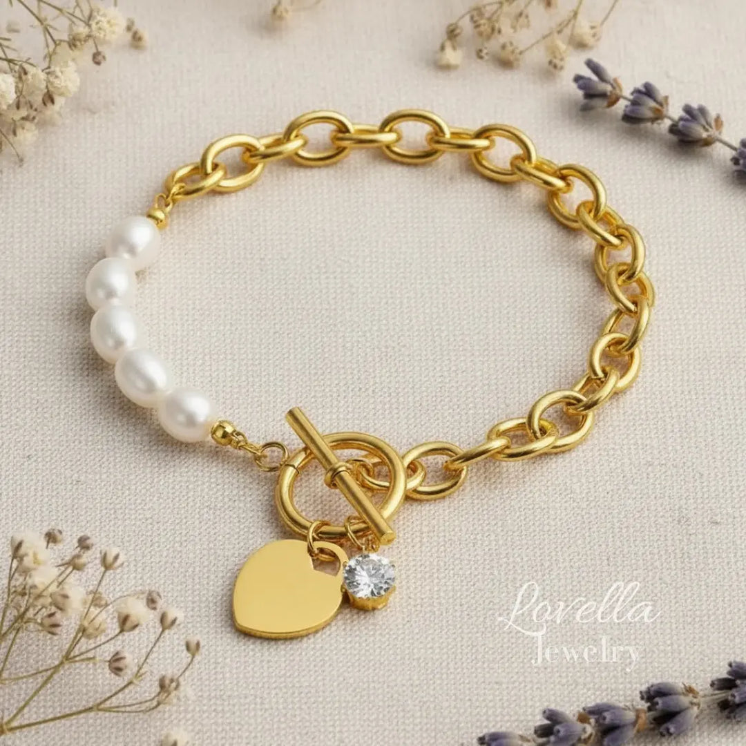 Gold bracelet with heart charm and pearl beads on a beige background