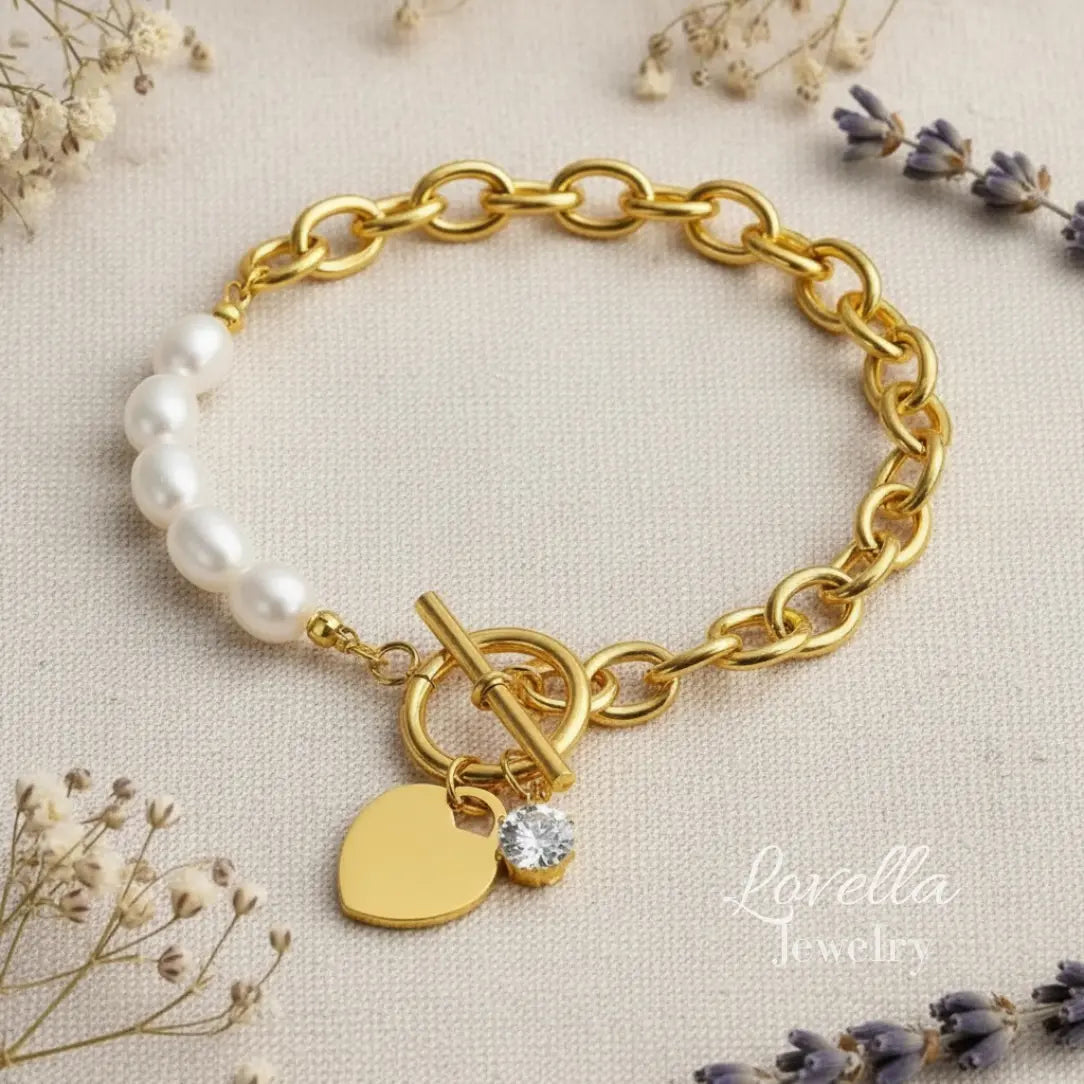 Gold bracelet with heart charm and pearl beads on a beige background