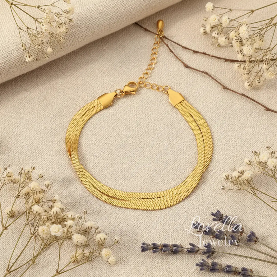 Gold bracelet on a textured surface with dried flowers
