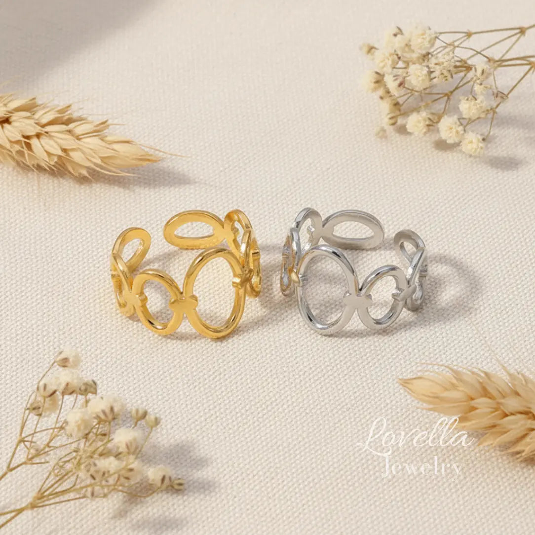 Two rings, one gold and one silver, on a textured surface with dried flowers.