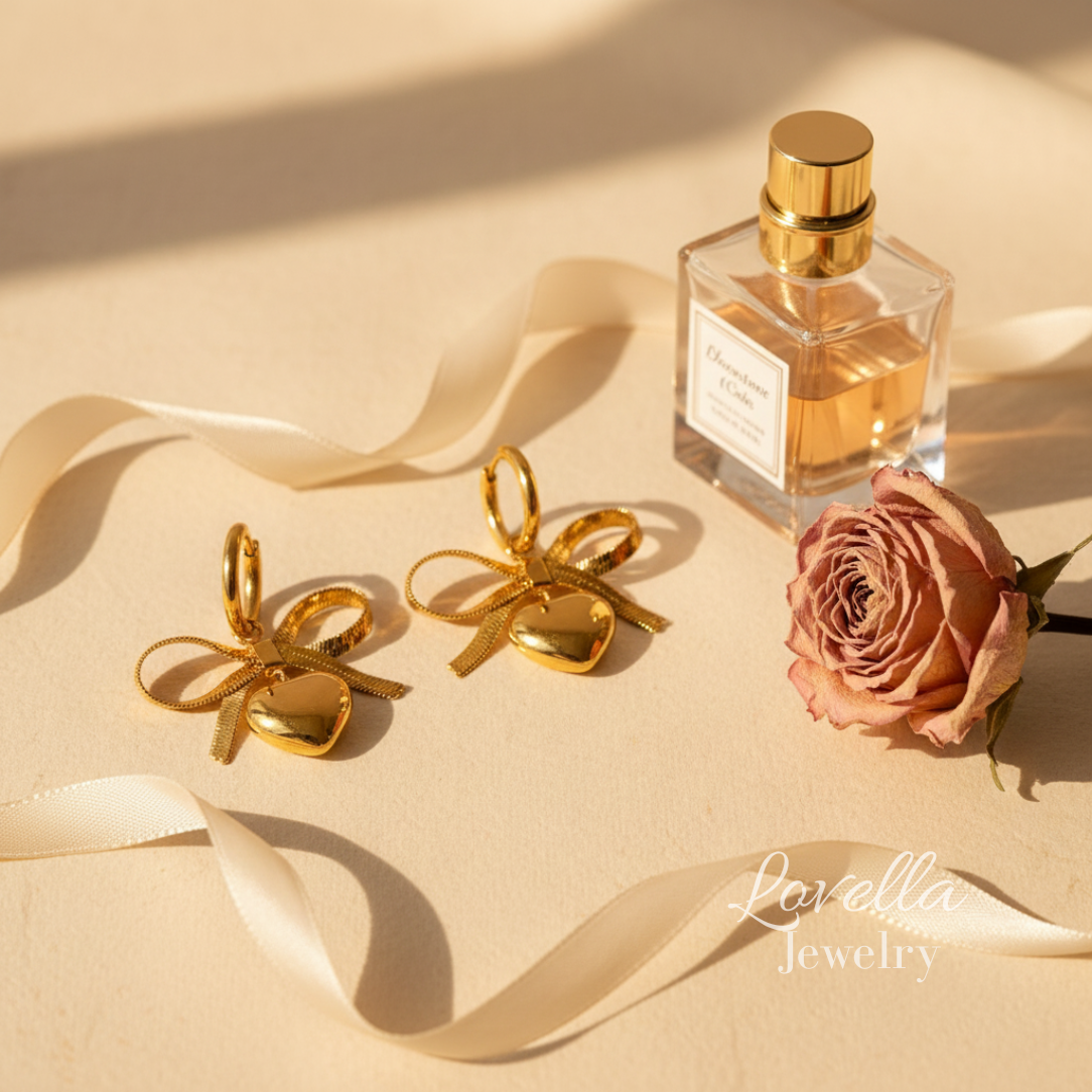 Gold bow-shaped earrings, a perfume bottle, and a rose on a beige surface
